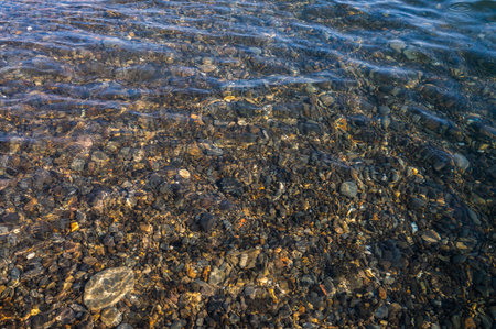 Underwater pebble backgrounds. Colorful stones sea bottom in the sun rays. View from above through clear water. Seascape wallpaper texture. Soft focus.の写真素材