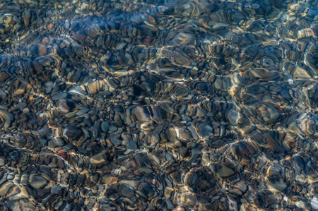 Underwater pebble backgrounds. Colorful stones sea bottom in the sun rays. View from above through clear water. Seascape wallpaper texture. Soft focus.の写真素材