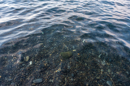 Underwater pebble backgrounds. Colorful stones sea bottom in the sun rays. View from above through clear water. Seascape wallpaper texture. Soft focus.の写真素材