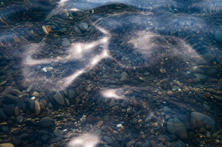 Underwater pebble backgrounds. Colorful stones sea bottom in the sun rays. View from above through clear water. Seascape wallpaper texture. Soft focus.の写真素材