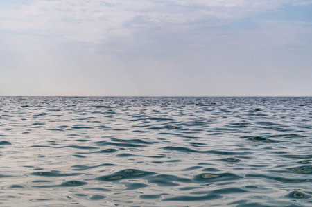 Blue sea surface with to the horizon. Sea waves with cloudy sky. Abstract background of water flow in ocean, sea, river, lake. Seascape wallpaper.の写真素材