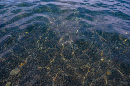 Underwater pebble backgrounds. Colorful stones sea bottom in the sun rays. View from above through clear water. Seascape wallpaper texture. Soft focus.の写真素材