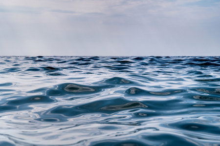 Blue sea surface with to the horizon. Sea waves with cloudy sky. Abstract background of water flow...
