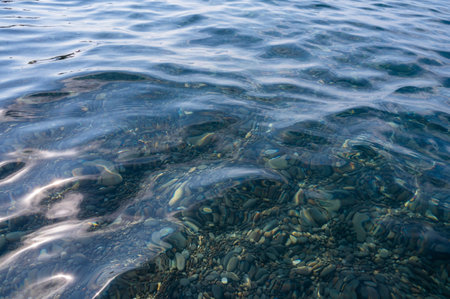 Underwater pebble backgrounds. Colorful stones sea bottom in the sun rays. View from above through clear water. Seascape wallpaper texture. Soft focus.の写真素材