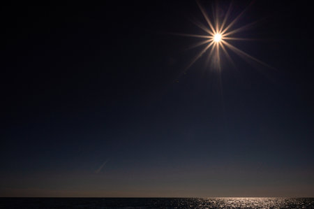 Sun starburst over the sea on sunny day. Ocean waves with sky in horizon. Sparkling sea water.