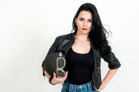 Fashion portrait of sexy stunning hipster woman, bright make up, vintage sunglasses, biker leather jacket, trendy jewelry and accessorizes. Urban wall background. Photoshoot relaxed bikerの写真素材