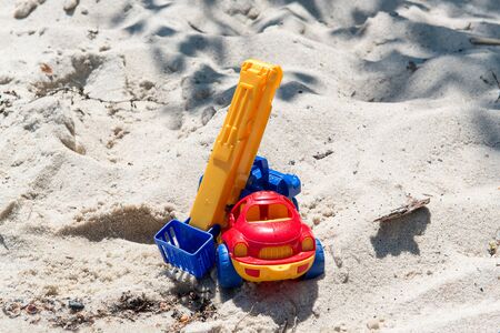 Toy truck with a boom in the wet sand. Summer holidays at sea. Special miniature.
