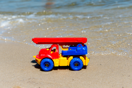 Toy truck with a boom in the wet sand. Summer holidays at sea. Special miniature.の写真素材
