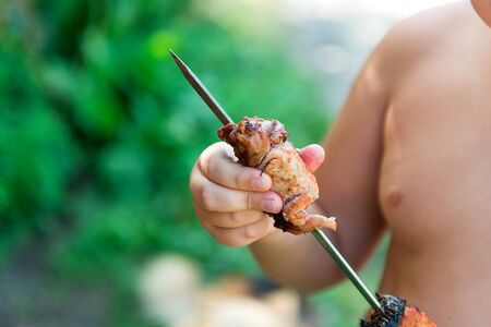 Tubby boy with pleasure eats a shish kebab. Camping. Healthy nutrition and diet.の写真素材