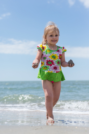 A child, a little girl playing fun on the seashore in the summer.の写真素材