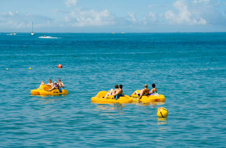people in a yellow pedal boat  close to beachの写真素材