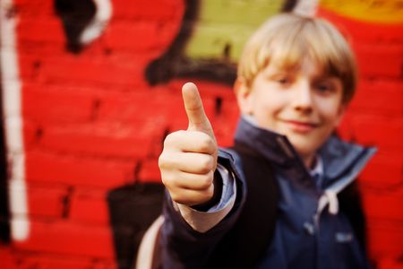 Cool kid standing in front of a graffiti wall. Focus in hand (selective DOF)の写真素材