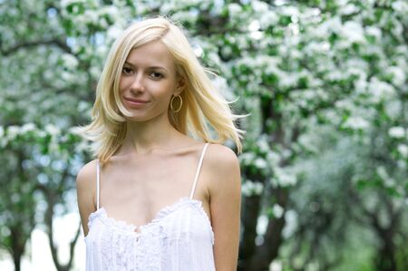 Young beautiful woman in a white dress in blooming gardensの写真素材