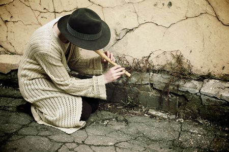Young girl in a hat playing flute on the streetの写真素材