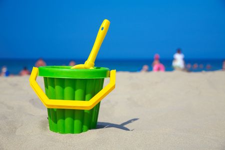 Yellow plastic spade and green bucket in sandの写真素材