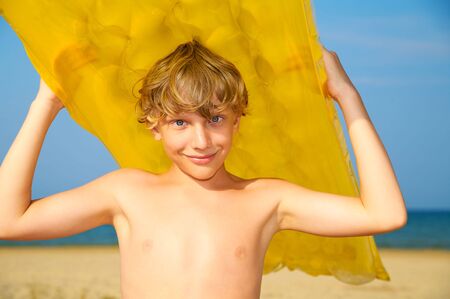 Young boy with air mattress on summer beachの写真素材