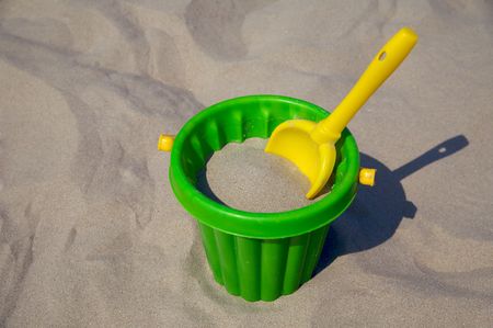 Yellow plastic spade and green bucket in sandの写真素材