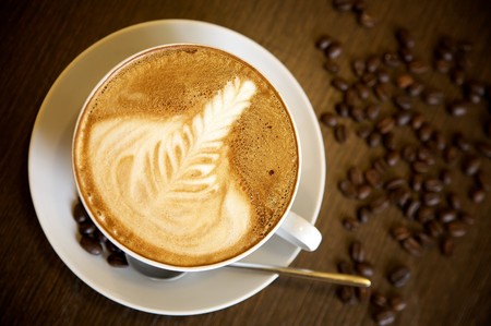 Latte art on a cappucinno and coffee-beans (selective DOF)の写真素材