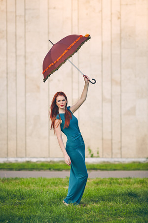 Portrait of beautiful red-haired young woman with umbrellaの写真素材
