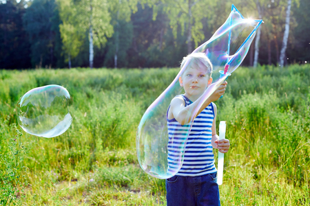 Little blond boy makes bubbles soap outside in a park. Ð¡hildhood conceptの写真素材