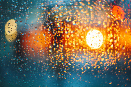 Headlights through glass with rain drops. Blur bokeh, defocused backgroundの写真素材