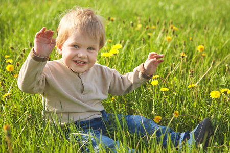 Happy childhood outdoor, little blond boy in green grassの写真素材