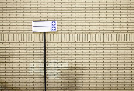 Information sign with arrows, detail of a brick wall with a signal indicationの写真素材