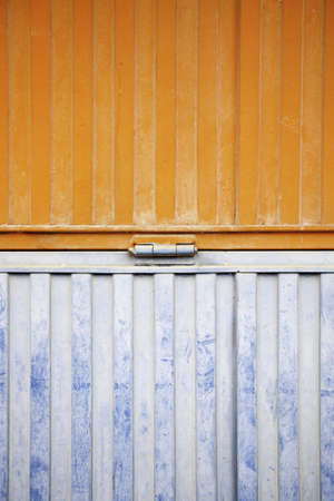 Wall decorated metal, detail of a closed metal door, painted in orange and blueの写真素材