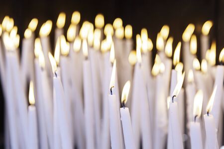 Burning candles in a church, detail of lighted wax candles to pray Christian tradition, faithの写真素材