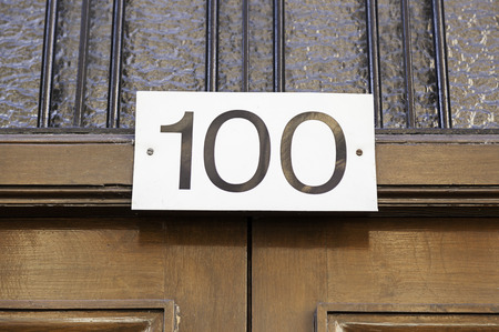 Number one hundred on a wall, detail of a number of information in a house in the cityの写真素材