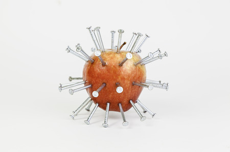 Apple stuck with nails, detail of a fruit with iron, abstract, healthy food, fruit