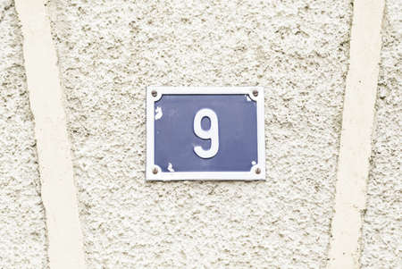Number nine on a wall, detail of a wall with a number of information, odd numberの写真素材