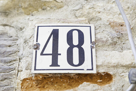 Number forty-eight on the wall of a house, detail of a number of information, even number