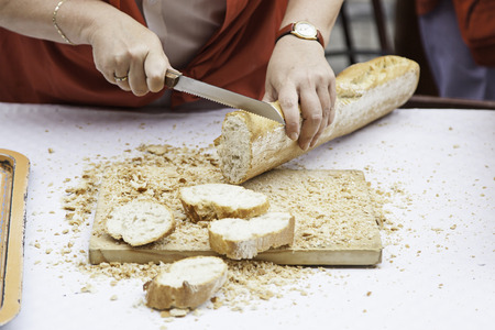 Cutting bread in a store, detail of hands cutting with a knife
