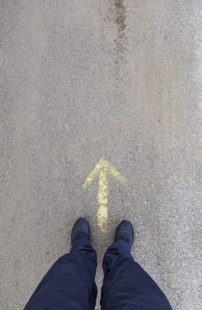 Feet in front of an arrow, detail of a direction arrow, sign
