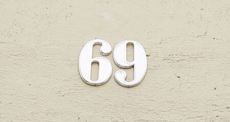 Number sixty nine on the wall of a house, detail of a number of information, odd numberの写真素材