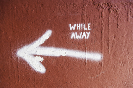 Arrow on a wall with text, detail of an indication, while awayの写真素材