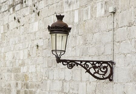 Old street lamp on a wall, detail of city lighting, electricity and lightの写真素材