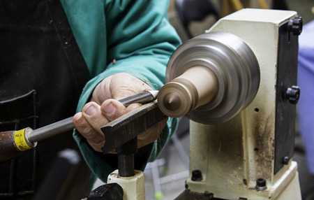 Man working with a lathe wood, detail of manual work, shaping wood