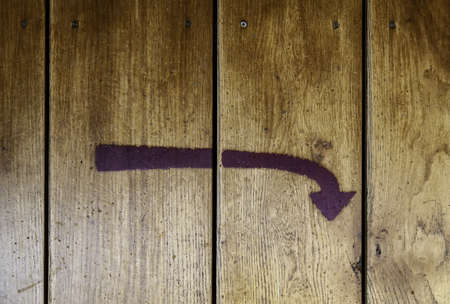 Directional arrow painted on wood, detail of information sign