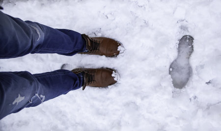 Detail of men's boots on a snowy day in winter, cold and iceの写真素材