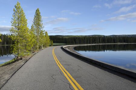 road with water on two sides of Lake Yellowstone in Wyoming in Americaの写真素材