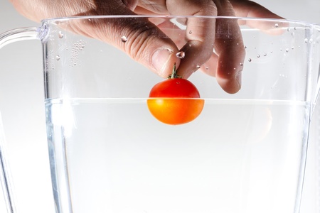 hand that is throwing a tomato in waterの写真素材