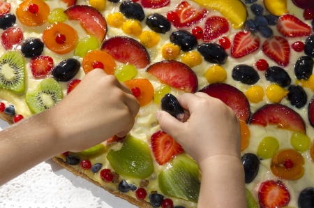 children steal from a fruit cakeの写真素材