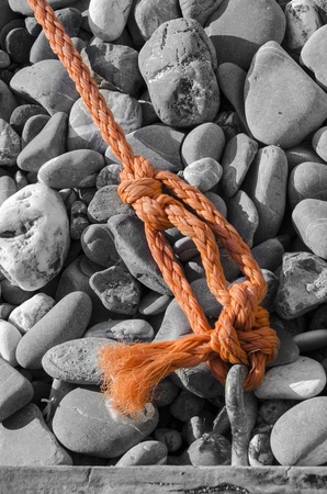 orange rope on the beach of gray stonesの写真素材