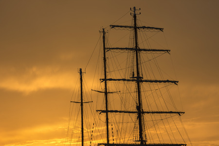 sailing ship in the harbor at sunset in Genoaの写真素材