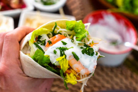 man holding typical Mexican fajita with shrimp and vegetablesの写真素材