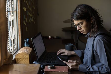 man with long hair and glasses working from home on financial issuesの写真素材