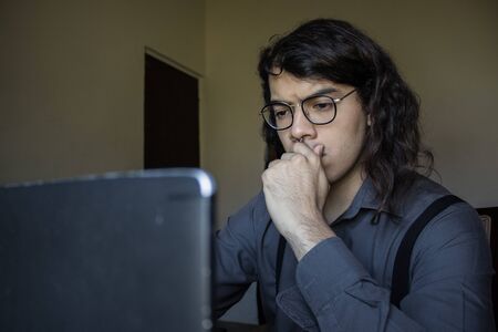 man with long hair and glasses working from home on financial issuesの写真素材