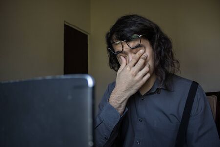 man with long hair and glasses working from home on financial issuesの写真素材